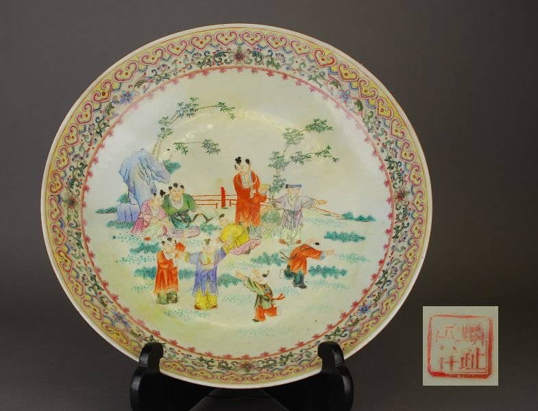 C19th/20th Chinese famille rose charger painted with: C19th/20th Chinese famille rose charger painted with young boys playing in a garden surrounded by ruyi-head border with multi-coloured lotus sprays, four-character mark to base, 37 dia