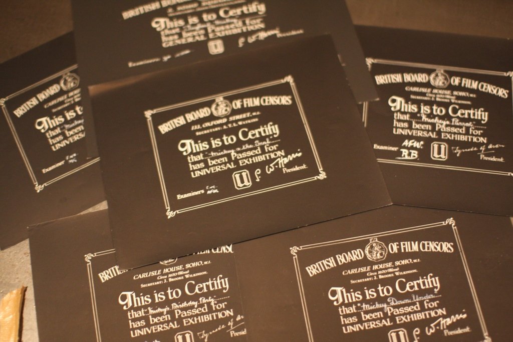 Disney Mickey Mouse BBFC Certificates: Disney Mickey Mouse. A collection consisting of 5 1940/50’s and 1 1960’s larger British Board Of Film Censors Certificates Signed by the examiner in white ink Graphite black paper Dimensions 25.5c