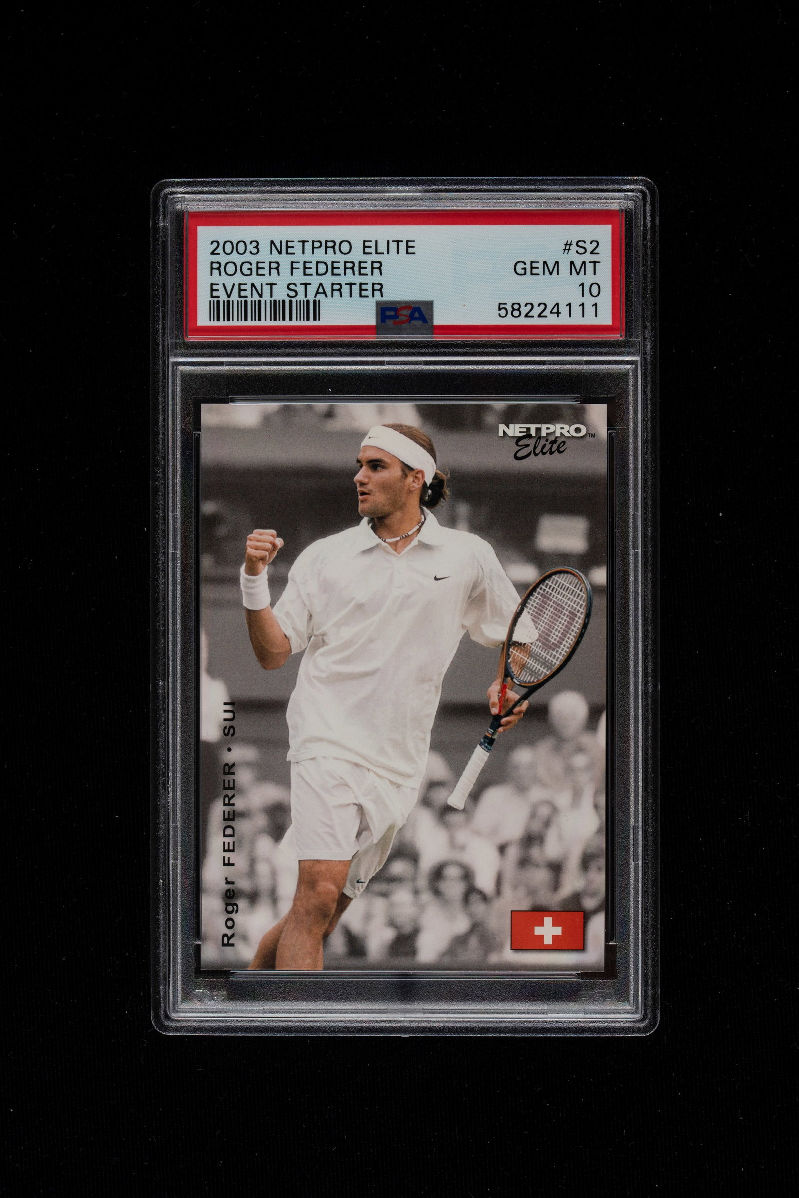 Roger Federer - Graded card - Netpro Elite - Event Starter - 2003 - PSA 10: A PSA 10-grade card of Roger Federer from 2003, part of the Netpro Elite set. The card captures a young Roger Federer in a moment of celebration, with a clenched fist and racket in hand. Federer is we