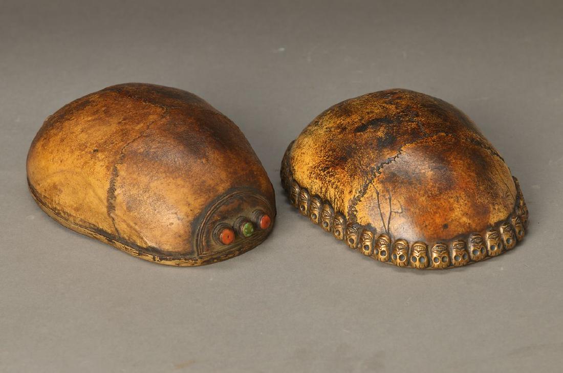 two scull bowls, Tibet, around 1900, interior silver: two scull bowls, Tibet, around 1900, interior silver plated, 1 with encircling sculls, silver gilt, 1 with colorful stone setting, L.approx. 17 cm, traces of age