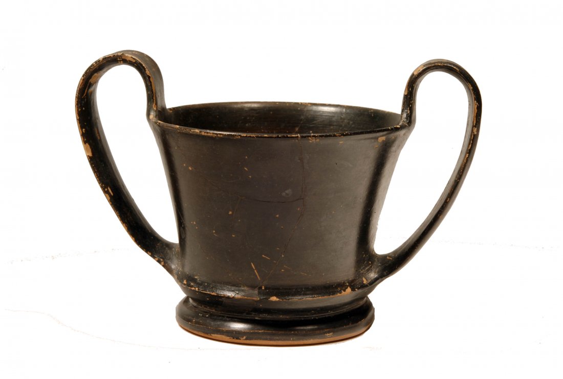 Ancient Attic Black Glazed Pottery Kantharos: Greek, Ca. 500 BC. Open black-ware vessel on ring base with high twin strap handles at either side of rim. Height: 5 inches; Width: 7 inches (handle to handle). Ex German private collection.