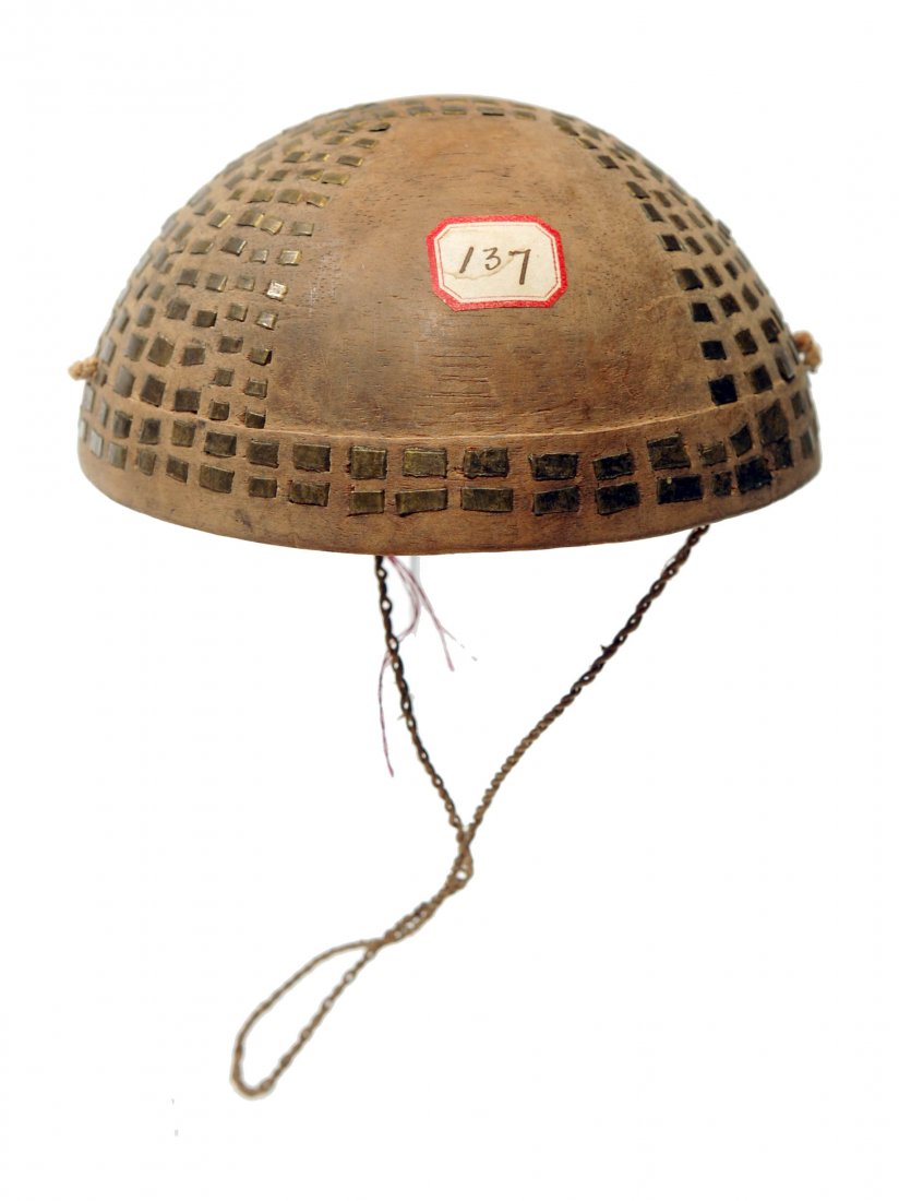 Filipino Head Cap from the Philippines: Small circular filipino child's cap, carved in wood with copper studs arranged in a geometric pattern, with cord strap and old inventory label. Diameter: 4.75 inches. Ex. New York collection acquired