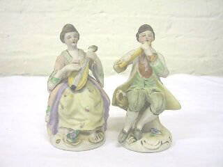 Pr. Seated Occupied Japan Musical Figurines.: Both man and woman are seated and playing musical instruments. The man is 5" tall and playing the flute. He is stamped Made in Occupied Japan. The woman is 5" tall and playing a string instrument.
