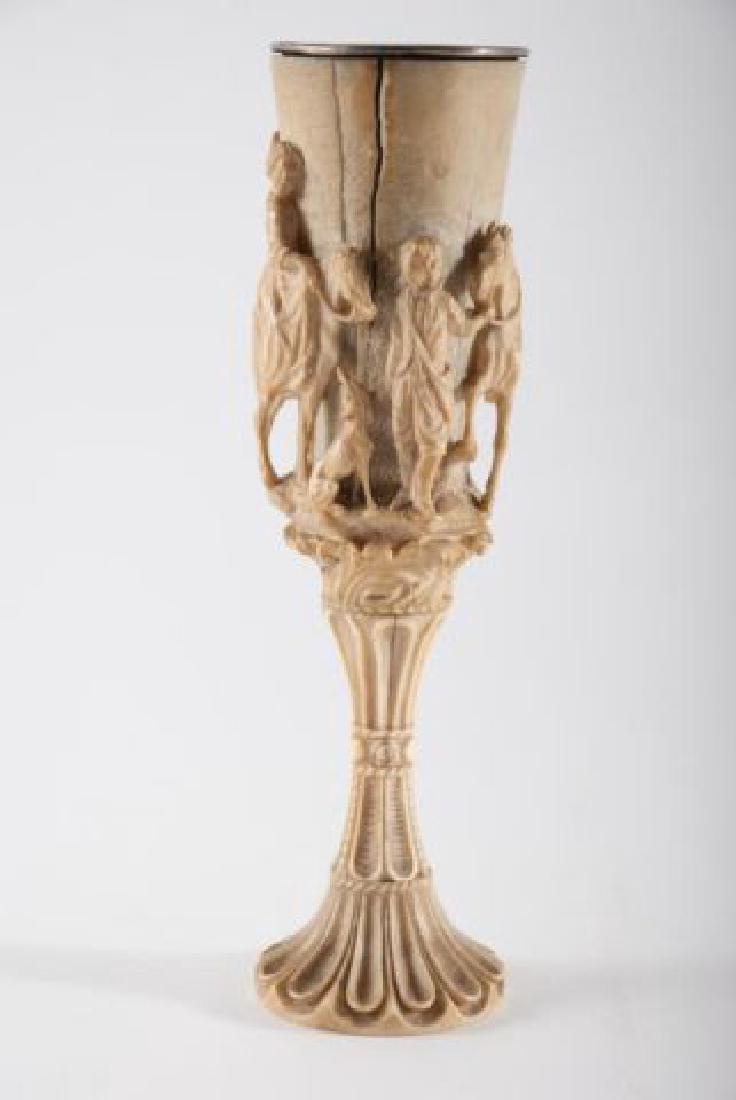 (17th c) CONTINENTAL CARVED WINE CUP: Carved in high relief with horses, dog and riders. Base which screws to cup is deeply carved with petals. Silver cup inset into carving. Height 7 inches. Condition: Age cracks (see photographs)