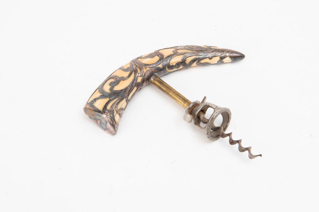 STERLING SILVER OVERLAY BOARS TOOTH CORKSCREW: Marked "Sterling" on underside; silver wraps around tooth and is engraved with acanthus leaf decoration. 6 1/4 x 6 1/4 x 3/4 inches