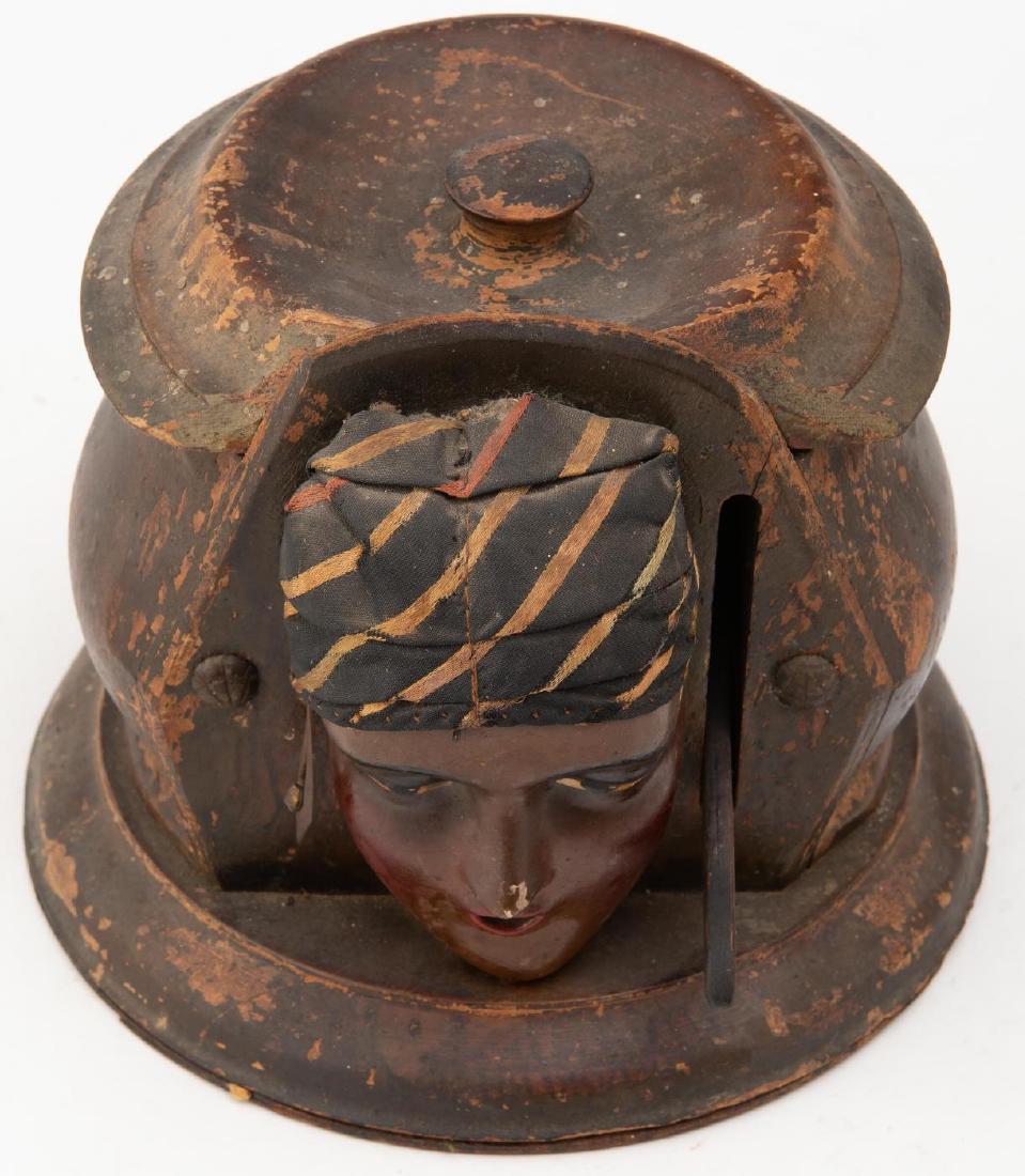 PAINTED MOORISH MAIDEN CIGARETTE DISPENSER: Early 20th century; In old paint; wooden mechanism; head covered with stripped cloth turban; Lever on right dispenses cigarette out of mouth.6 x 7 x 7 inches