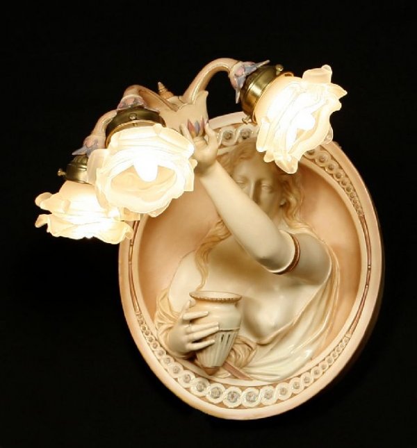 Royal Worcester figural three-light wall sconce.: Royal Worcester figural three-light wall sconce. The well-molded oval three-quarter length figure of a woman holding a vase in right hand and the left arm extended holding an electrolier With three fr