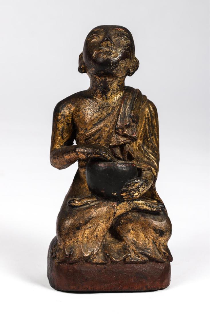 ASIAN CARVED AN GILT BUDDHA: Seated and holding an alms bowl. Carved from a single piece of wood. 7 inches.