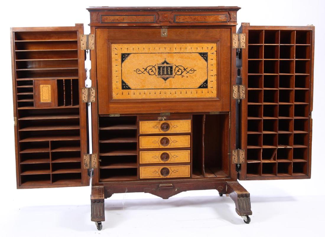 FINE AMERICAN RENAISSANCE WOOTON PATENT DESK: Typical form with all-over foliage and scrolls. Ornamental doors feature letter slot and Wooton Patent plaque. Interior with leather writing surface and varied compartments and drawers. 68 x 46 x 34 i