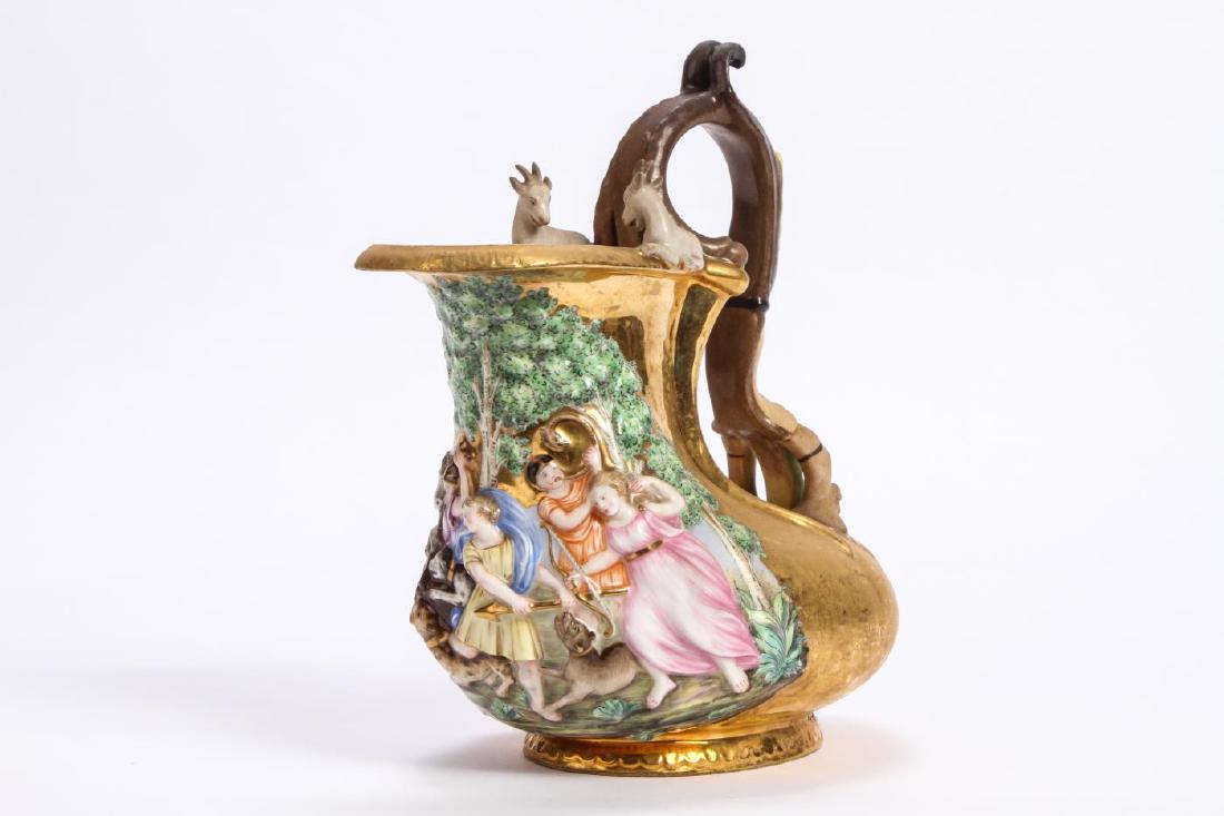 CAPODIMONTE PORCELAIN GILT FIGURAL PITCHER: "The Boar Hunt" in polychrome raised relief with full figured goats on rim and scrolled handle with horns, foliat and cherub. 7 x 9 x 5 inches.