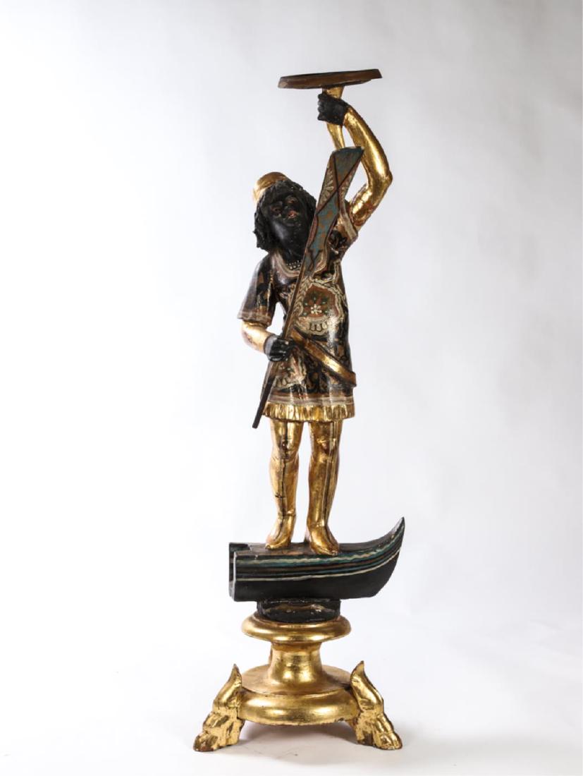 (19th c) VENETIAN BLACKAMORE STATUETTE: Stands on a gondola prow while holding tray and paddle. Raised on a gilt base with carved hoof-form feet. Carved, gilt and painted wood. 35 inches.