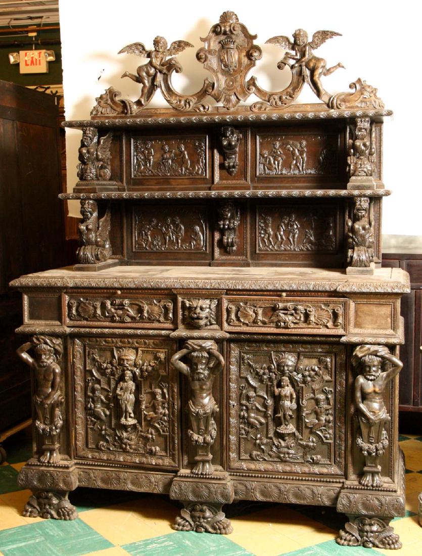 HEAVILY CARVED RENAISSANCE REVIVAL WALNUT SERVER: (Mid 19th c) Openwork crest surmounts two upper shelves supported by (4) griffin brackets and backed with (4) putti friezes flanking central figureheads. The cabinet's top edge is carved with acanthus