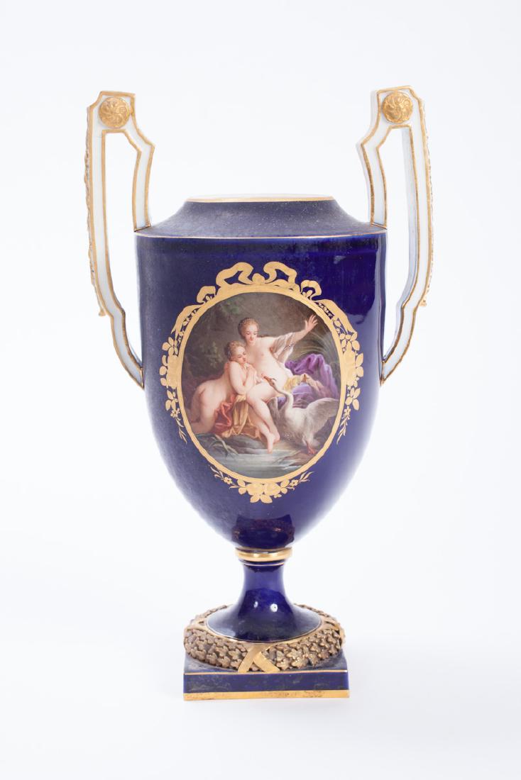 MEISSEN PORCELAIN URN: High-handled gilt and cobalt glazed porcelain vase with ormolu mounted wreath at base. Hand painted gilt ribbon cartouches on both sides depicts "Apollo and Daphne" and "Swan Seducing Two Nymphs". 10