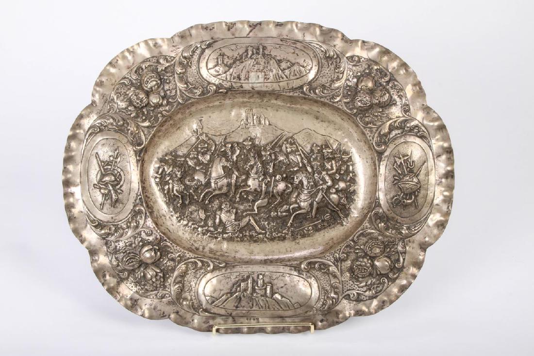 CONTINENTAL SILVER HALLMARKED CHARGER: Embossed with Battlescenes, 800 Silver broad rimmed charger embossed and chased with castles, weapons and battle scene. Hallmarked 800 and crossed hammers and arrows. Approx. 28 1/2 troy ounces. 17 x 