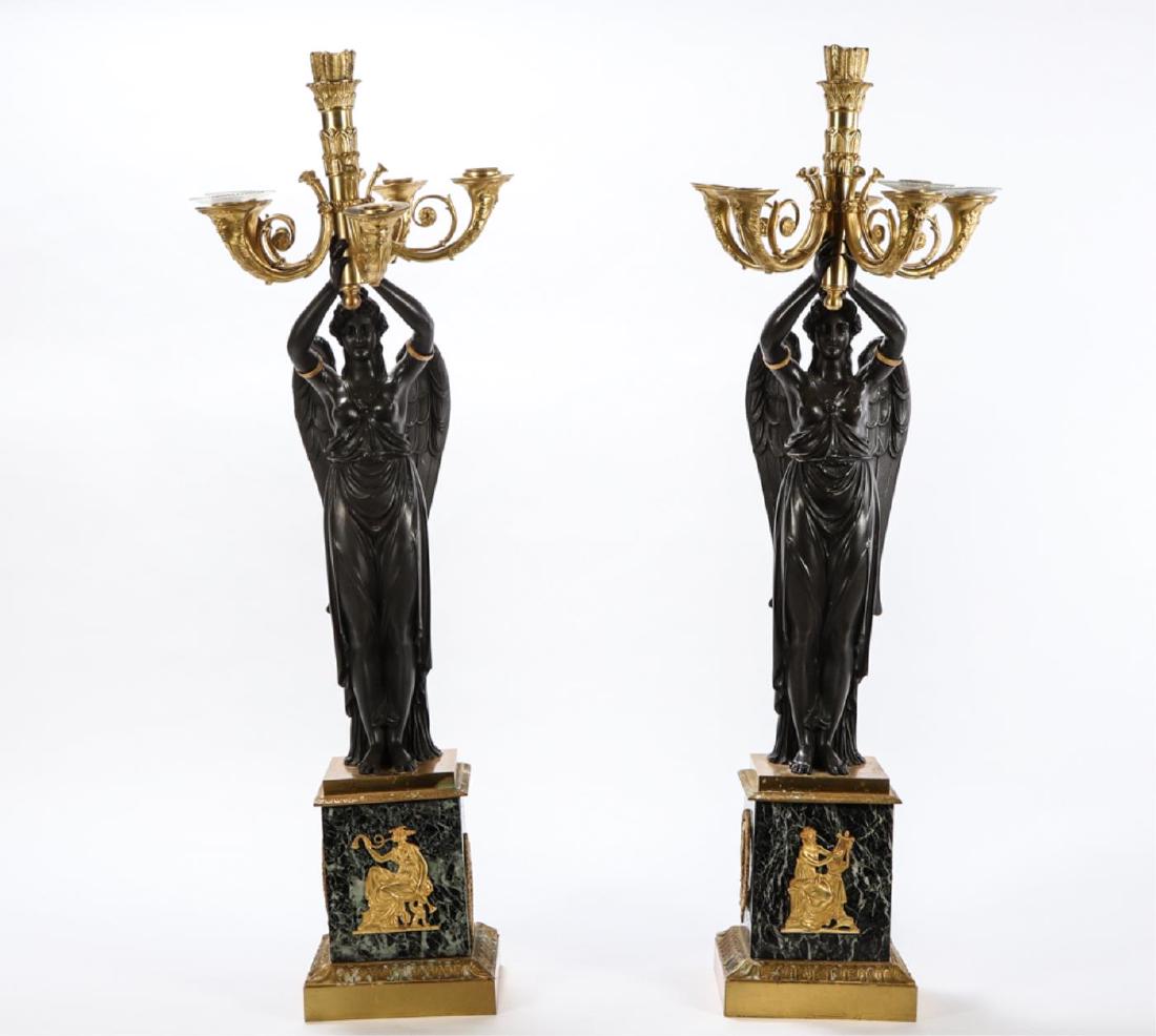 PAIR OF FRENCH EMPIRE STYLE FIGURAL CANDELABRAS: Circa 1920 having 5 lights surrounding a single light, surmounting a winged figure raised on a stepped square base with ormolu mounts, 36 inches.