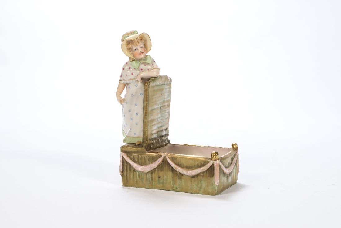 MEISSEN AMPHORA FIGURAL PIN BOX: Young Girl leans against large basket with pink ribbon swags. signed. 6 x 4 1/2 x 2 inches.