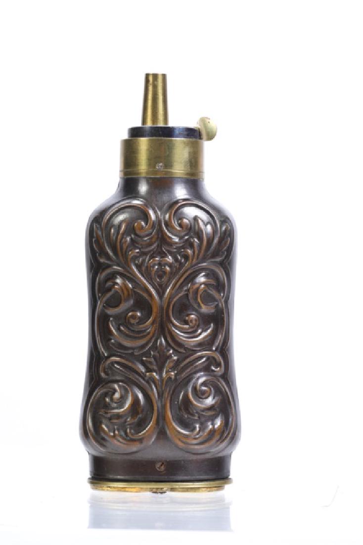 COPPER AND BRASS SHOT AND POWER FLASK: Embossed with foliated scrolls. Guild brass escutcheons open to (2) shot compartments. unmarked 5 inches.