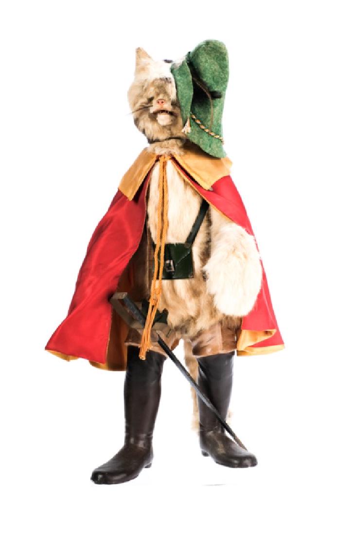 "PUSS IN BOOTS" AUTOMATON NODDER circa 1900: Fur-covered with green glass eyes, articulated jaw, long curved tail, papier-mâché boots and clockwork mechanism in the body causing him to nod and move his mouth as though speaking. 26 1/2 inches.