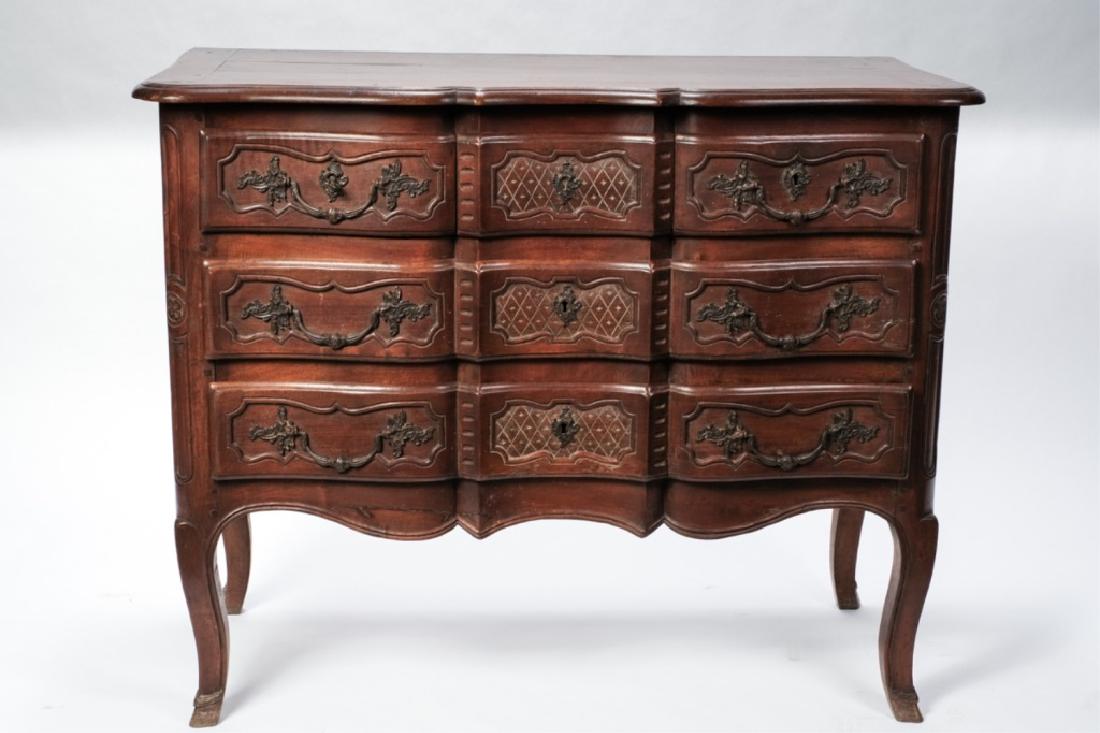 (18th c) FRENCH REGENCY FIVE DRAWER WALNUT CHEST: Scalloped serpentine paneled front with lattice-carved center and carved paneled sides. Bronze pulls cast with rococo escutcheons and serpentine apron. Cabriole legs terminating with hoof-carved feet.