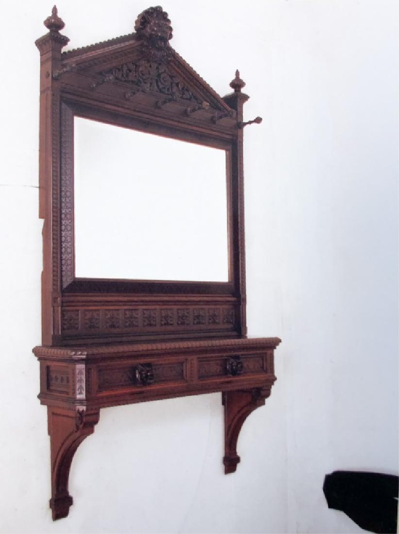 GOTHIC REVIVAL WALNUT MIRROR attr. to DANIEL PABST: Elaborately carved and pierced pediment with scrolls, an array of moldings and finials surmounted by an impressive lion's head. Beveled glass mirror is framed with carved repeating floral vines and fi