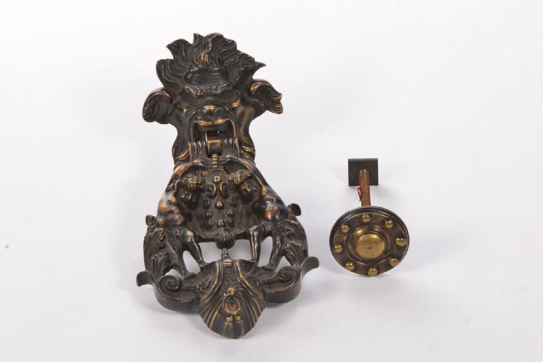 IMPRESSIVE FIGURAL BRONZE DOOR KNOCKER: Grimacing figure clutches striker with (2) cherubs, acanthus leaves and volutes in mouth. 10 inches.
