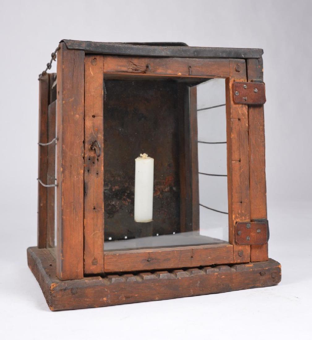 EARLY AMERICAN PRIMITIVE LANTERN: Single candle socket with wire guards, wrought iron swing handle and tin back. 10 x 9 x 9 inches.