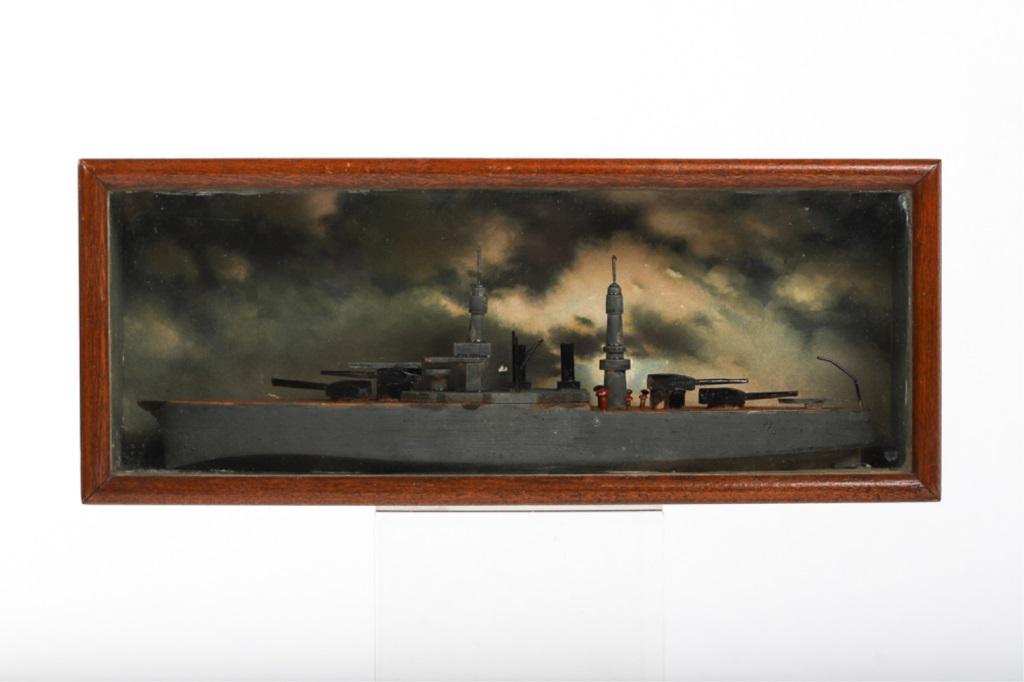 SHADOW BOX with a circa 1940 MODEL OF A BATTLESHIP: Carved and painted battleship is set into a glazed mahogany case with a background of printed seas and dramatic skies. 5 x 12 x 2 inches.