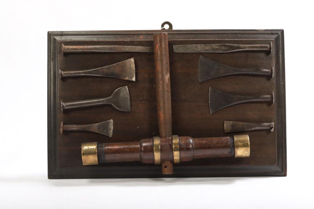 DISPLAY BOARD WITH TOOLS: TOOL display board of caulking tools and mallet. 8 irons, mallet with brass bands and rosewood head. Mounted on board 13 1/2" X 22".