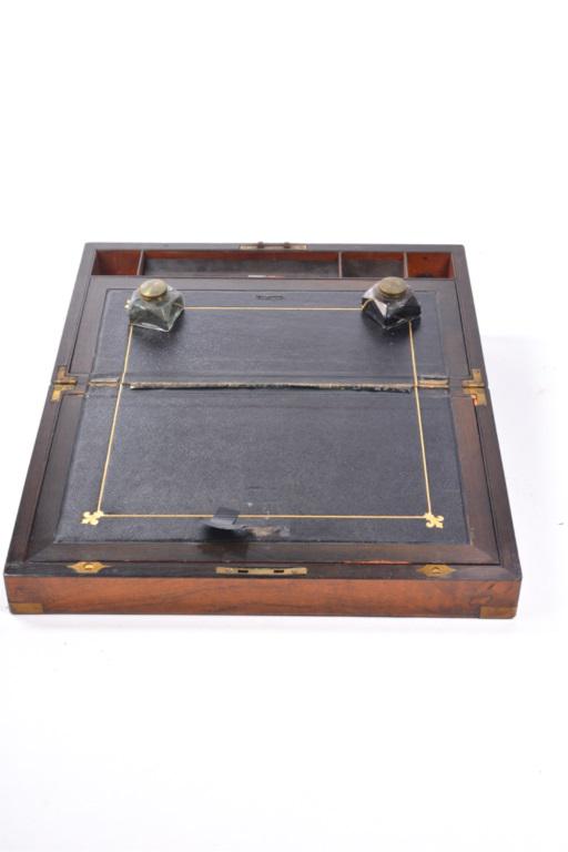 "ROBERT D. WILLKIE" MAHOGANY LAP DESK: DESK, mahogany portable desk with brass corners, 2 glass inkwells, key escutcheon and owners plaque "ROBERT D. WILLKIE NOV 1891". Interior leather writing surface worn, top storage panel is loose. 16"
