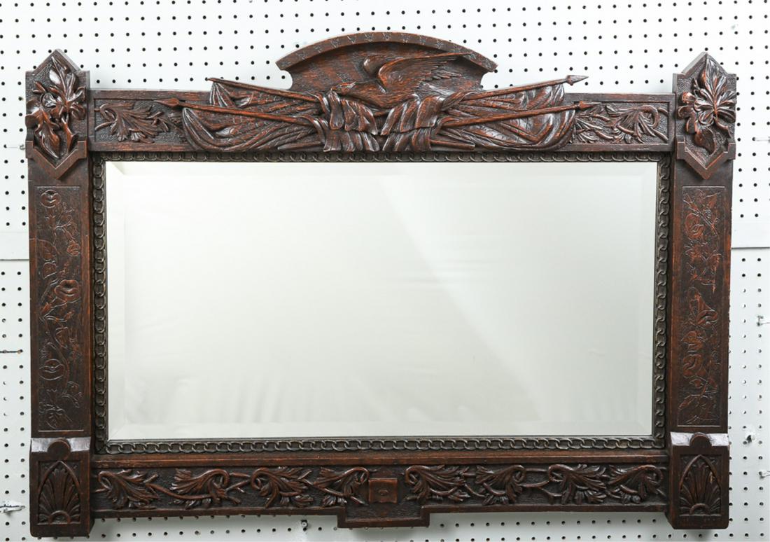 J.H. BROWN HAND CARVED PATRIOTIC MIRROR: With flying eagle and crossed American flags, vine and leaf foliate carved on all sides and bottom. 30" X 44" overall, beveled glass mirror measures 18" X 35". Signed by carver. J.H. Brown 1893