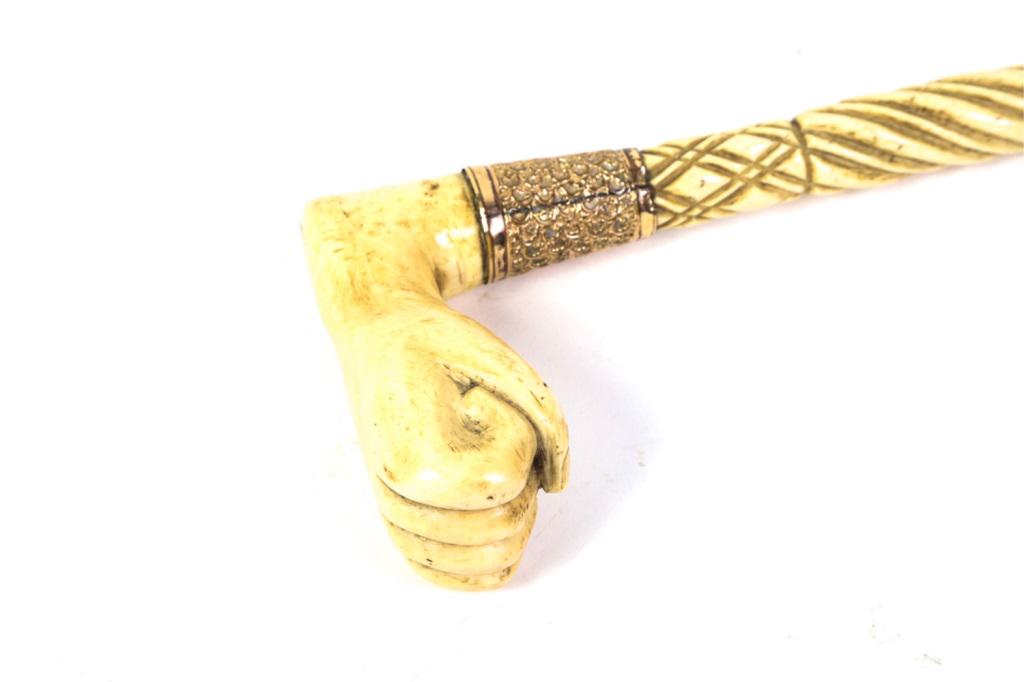 " H MUSSON"CARVED WHALEBONE CANE: CANE made of whale bone with a very large whale handle. The whale bone shaft is twist carved with a gold tone spacer with the name " H MUSSON". The very large handle is carved in the form of a hand wi