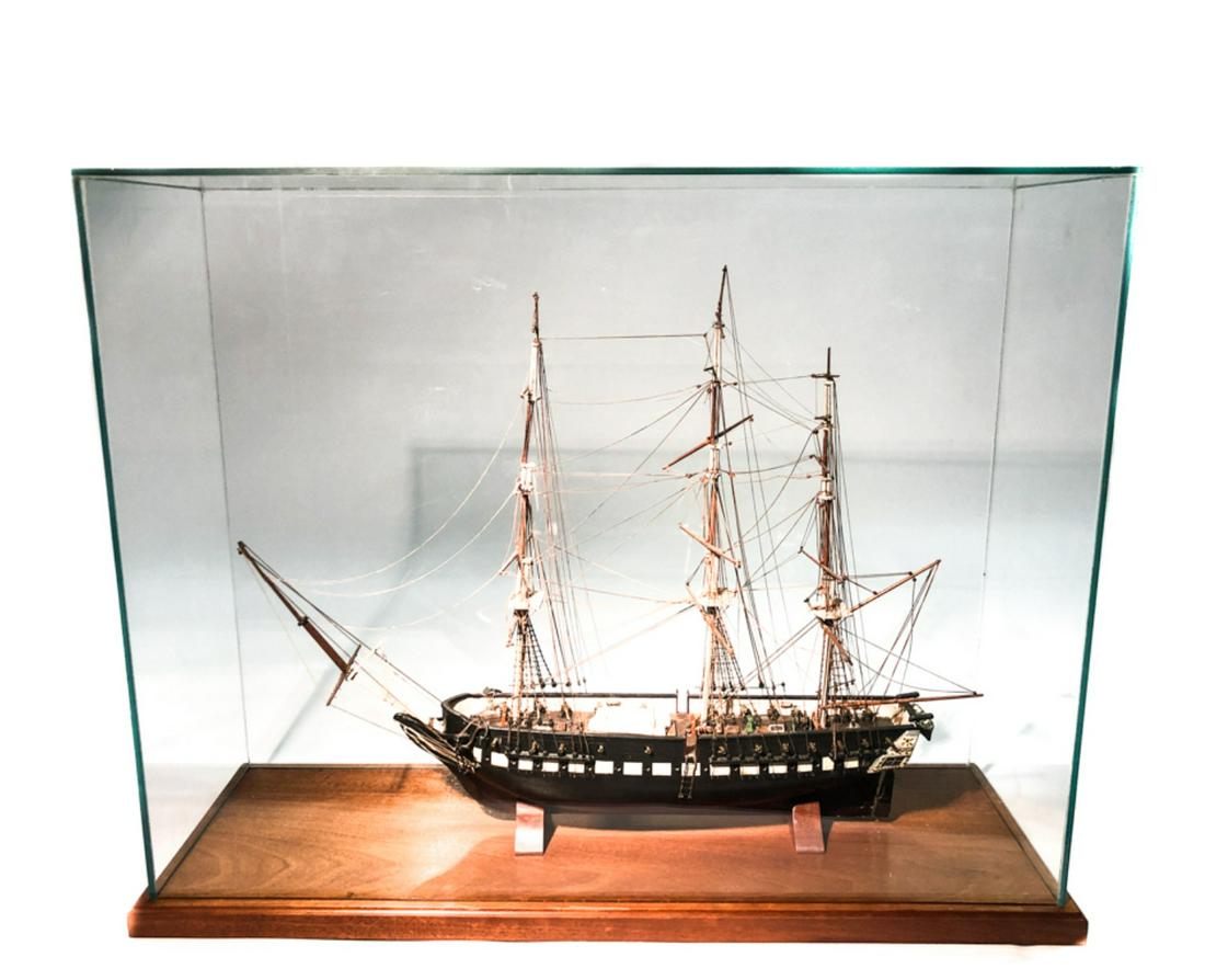 CASED SHIP MODEL OF A FULLY RIGGED SLOOP-OF-WAR: Carved and painted wood with brass cannons and deck furnishings. 25 x 36 x 12 inches.