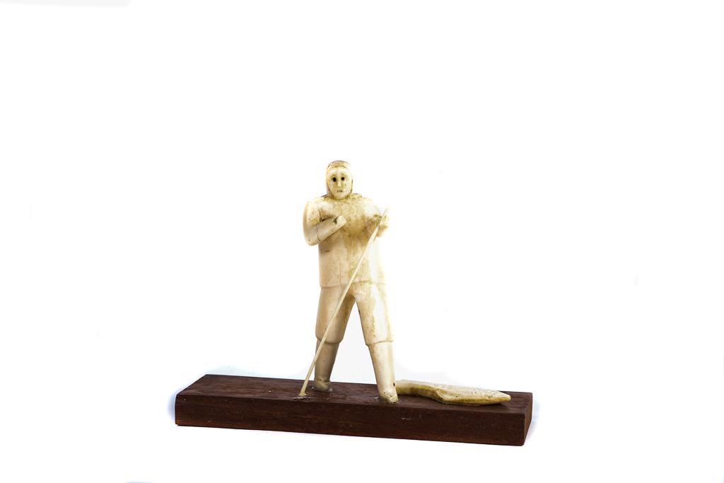 INUIT CARVING OF ESKIMO: CARVING of an Eskimo with harpoon in hand and a large halibut on base. Eskimo is 4" tall and made of walrus.