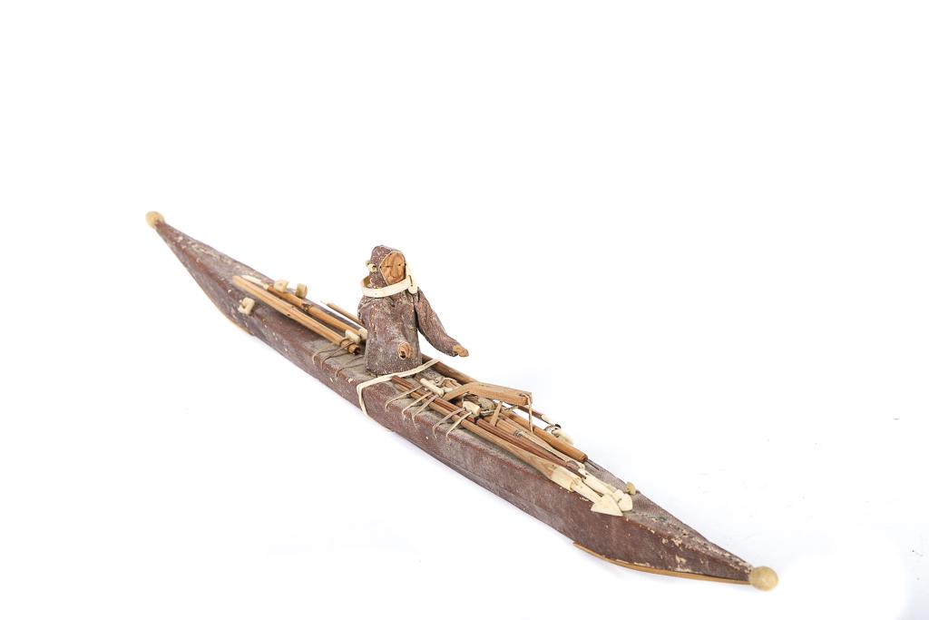 MODEL. KAYAK: MODEL, early model of an Eskimo kayak with treated seal skin covering. Bone fittings and sinew lashing. Kayak has many acc. including harpoons, lances etc. The wooden Eskimo is wearing his sealskin pa