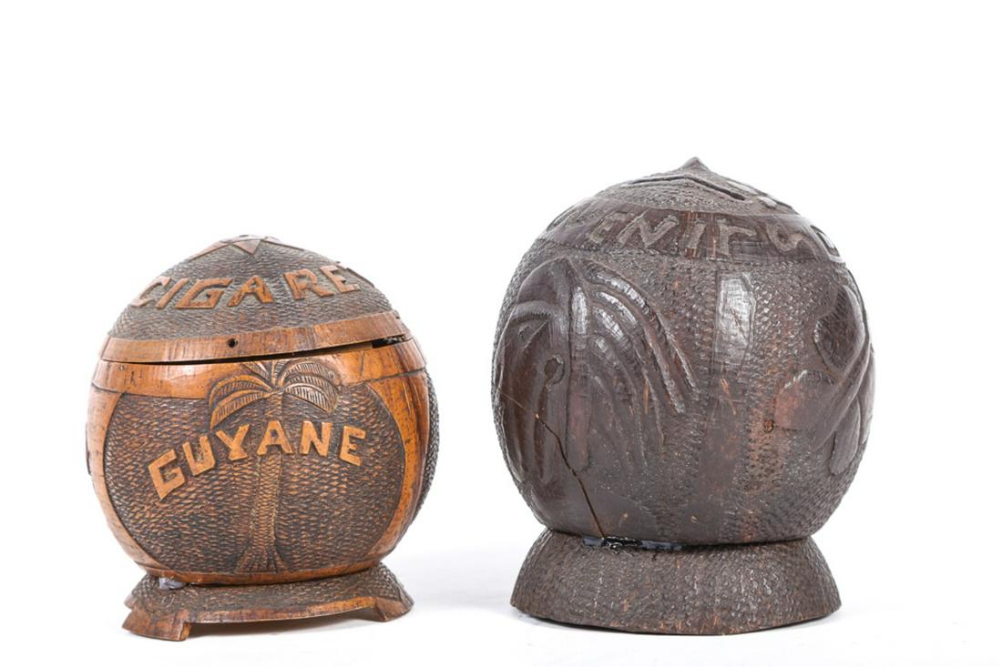 TWO SOUTH SEA COCONUT CARVINGS: A bank and the other is for 'CIGARETTES'. Bank with carved anchor, native & butterfly. The other is carved with a monkey, A smoking native and "GUYANE"