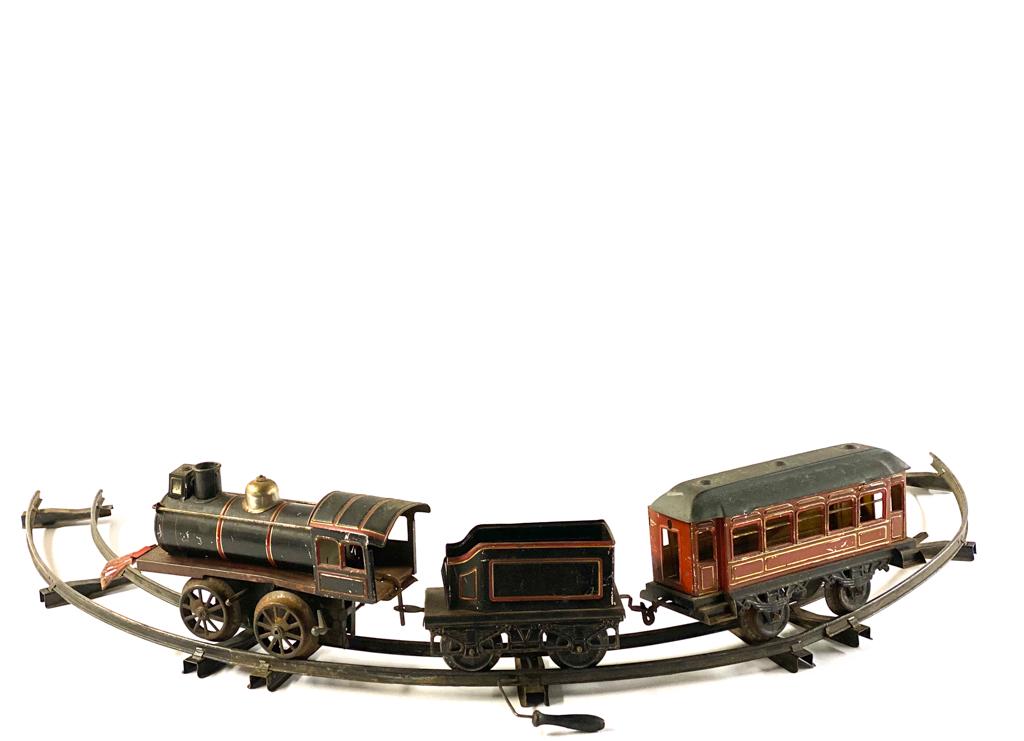 EARLY LIONEL KEY WIND TIN LOCOMOTIVE: Engine is approximately 9 inches in length. With coal and passenger car. Provenance: From the Estate of Michael Kenslea, Kittery, Maine.