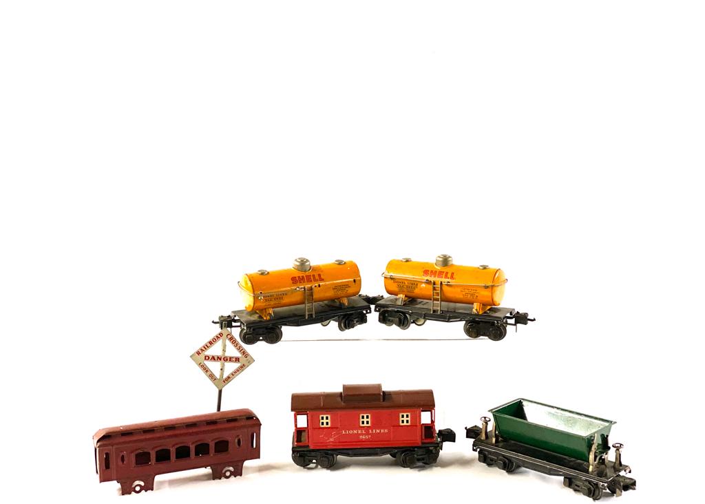 GROUP OF (5) LIONEL TRAINS: Two Shell Oil cars, coal, shell of passenger. All under 10 inches. Comes with tin sign. Provenance: From the Estate of Michael Kenslea, Kittery, Maine.