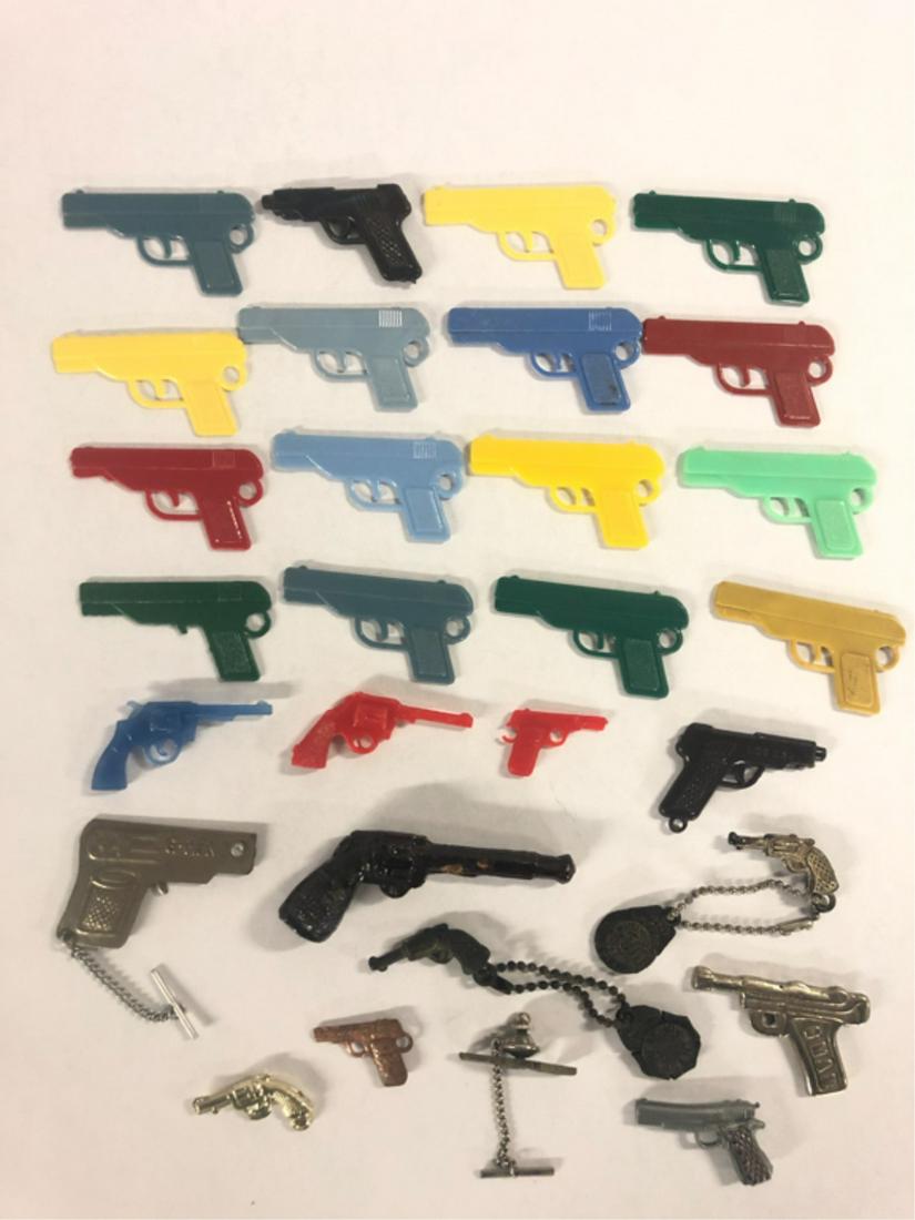(29) GUN PENDANTS AND TOYS: (2) Plastic guns in various colors 2" long, clay revolver pipe 3" long, (2) G Man gun pendants, (3) metal gun pendants, revolver tie pin, (2) Junior G Men key chains with revolver pendants From the co