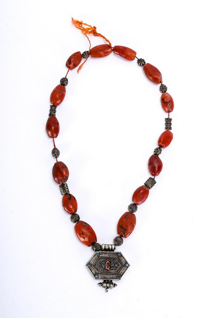 ANTIQUE TIBETAN GAU PENDANT NECKLACE: Comprising of a string of copper and red sherpa beads. Gau is decorated with silver filigree and set with stones. 24 inches.