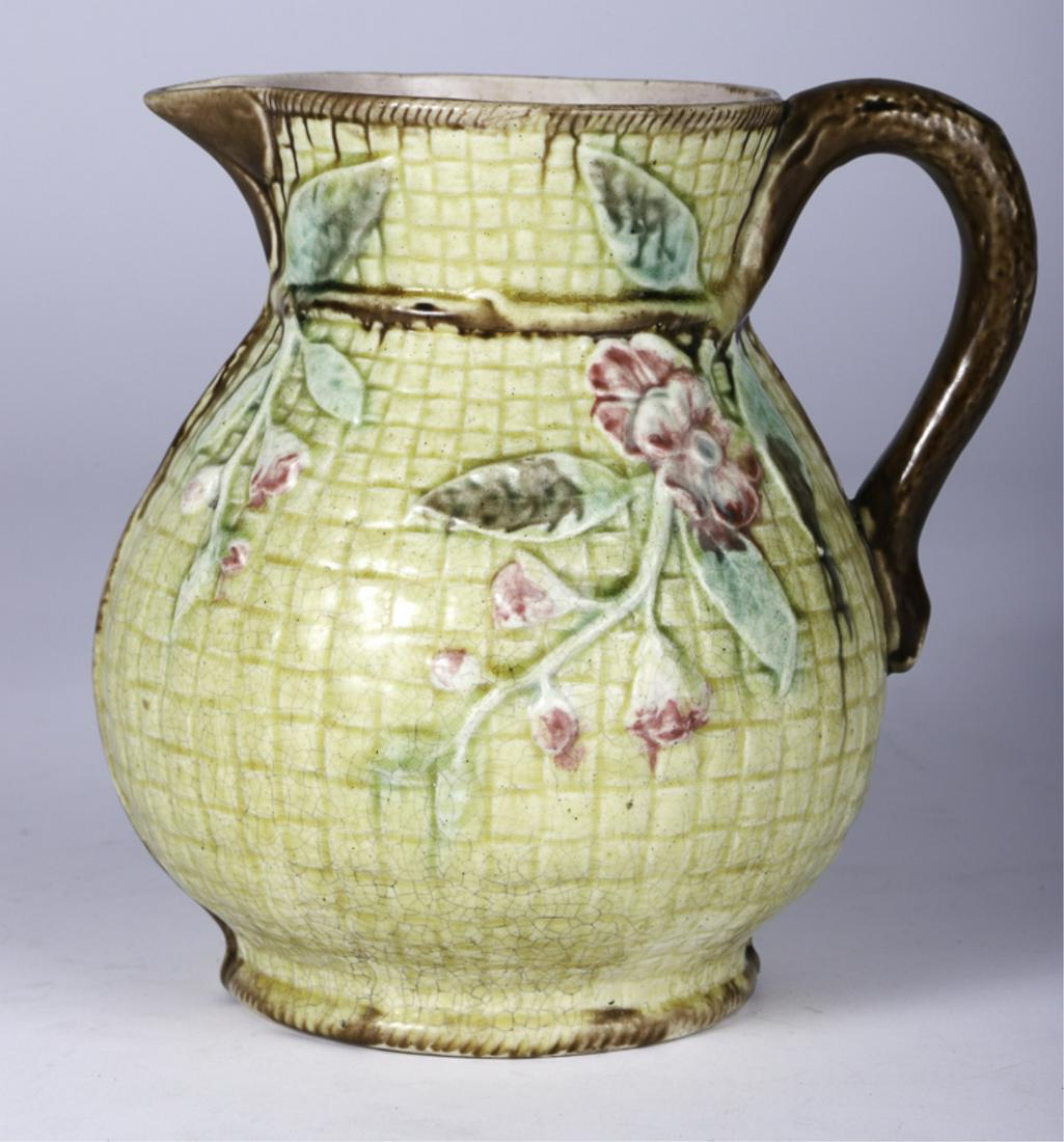MAJOLICA BASKET WEAVE PITCHER with PRUNUS: Antique Majolica earthenware pitcher with green basket weave design throughout with raised floral designs throughout and branch form handle. 7 1/2 inches