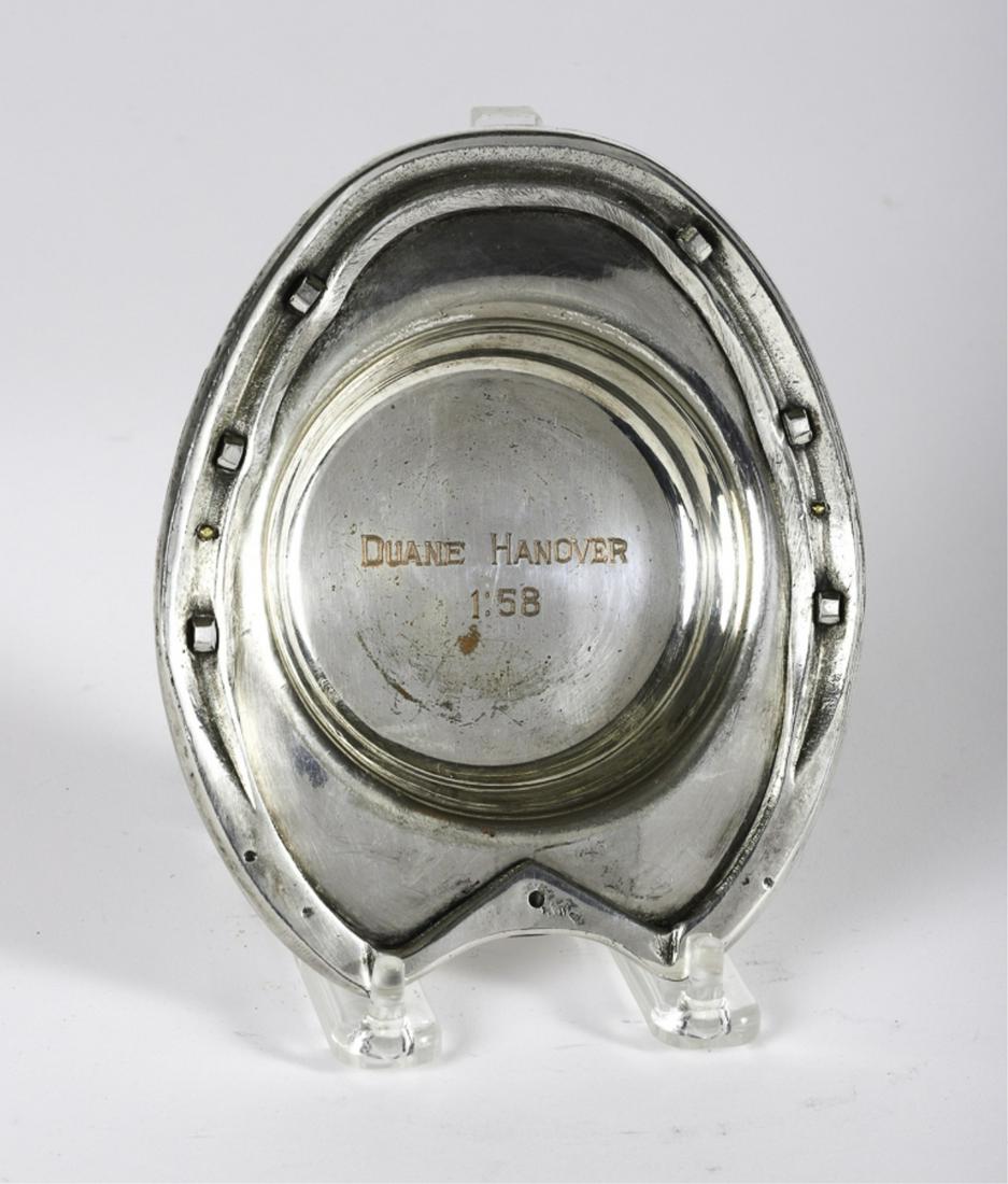DUANE HANOVER 1:58 PRESENTATION HORSESHOE COASTER: Artisan crafted bench made horseshoe laminated to base with brass pins. Silver over copper. unmarked. 1 x 5 x 6 inches.