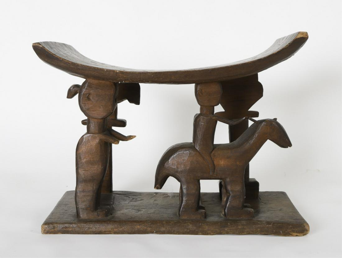 LARGE CARVED WOODEN WEST AFRICAN STOOL c1924: The seat supported by (4) different figures including a horse and rider, a human attendant, bird standing on a pole and a palm tree. 16 /4 x 22 x 12 inches Together with a sepia colored photograph of 