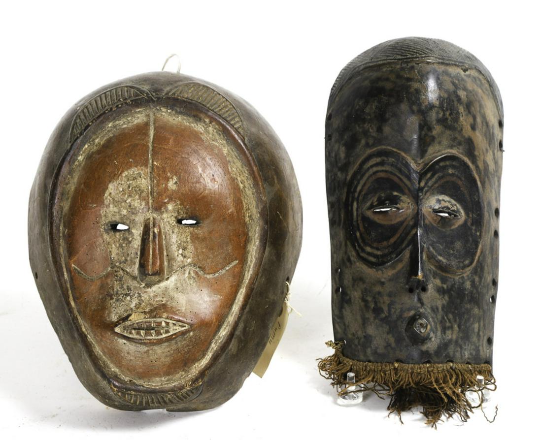 (2) WEST AFRICAN DANCING MASKS (Mid 20th c): Portraying a lion with a red stained and white face and a monkey. 12 inches (approx)