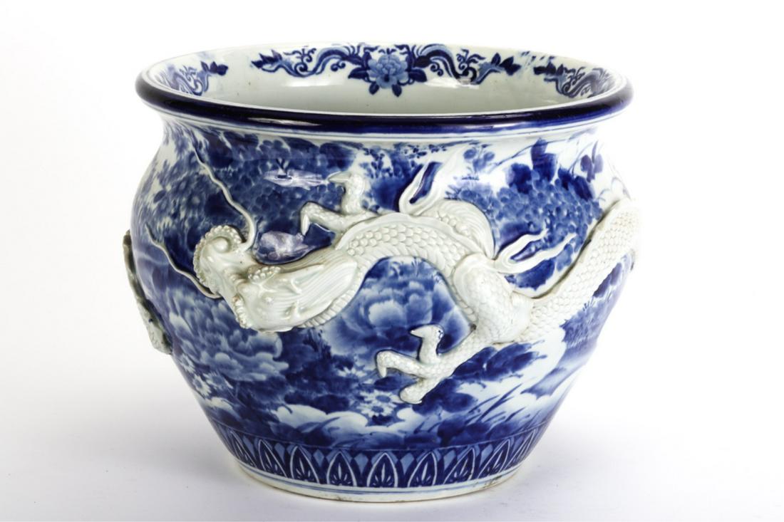 LARGE BLUE and WHITE CHINESE JARDINIERE w/ DRAGON: Raised sculptural dragon completely wraps around painted landscape with flowers, marsh and butterflies. unmarked. 12 x 16 inches.