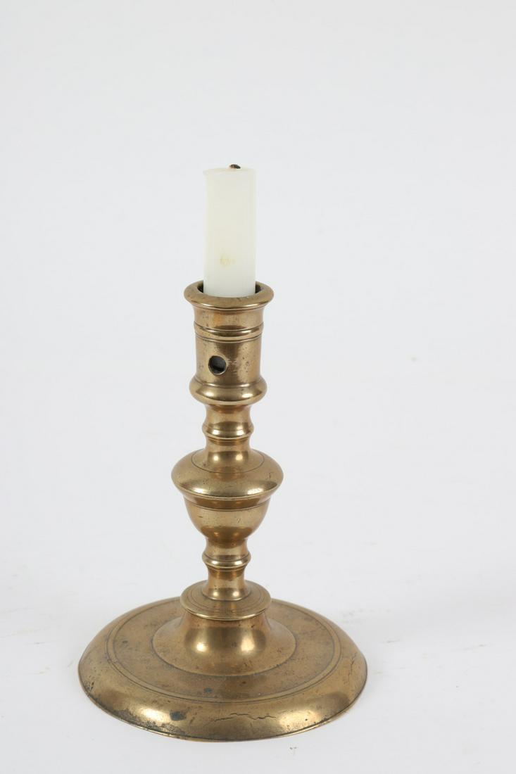 (17th c) Bell Metal Candlestick: Lateral aperture, acorn style and broad molded foot. 7 ½ inches