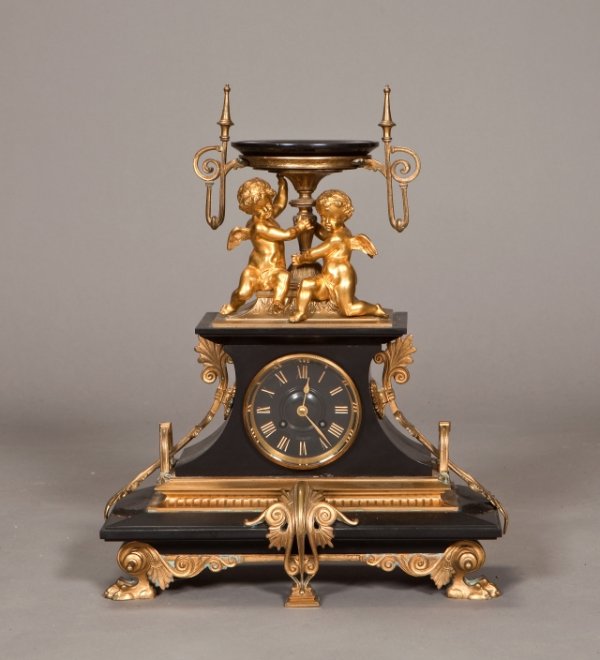 French Aesthetic form gilt bronze and black marbl: French Aesthetic form gilt bronze and black marble shelf clock with two gilt cupids supporting a two handled plateau. Height: 18 1/2 in. Width: 15 in.