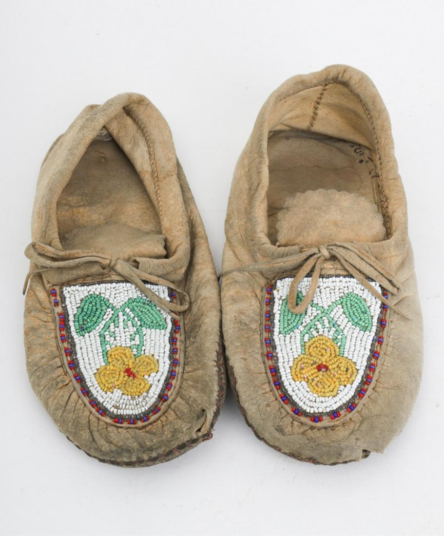 PAIR OF NATIVE AMERICAN BEADED MOCCASINS: Vamps decorated with beadwork flower motif. 9 1/4 inches