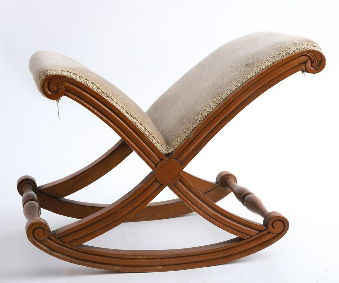 ROCKING UPHOLSTERED MAPLE FOOTSTOOL: X Construction with molded sides carved with volutes and scrolls. 14 1/2 x 18 x 13 inches.