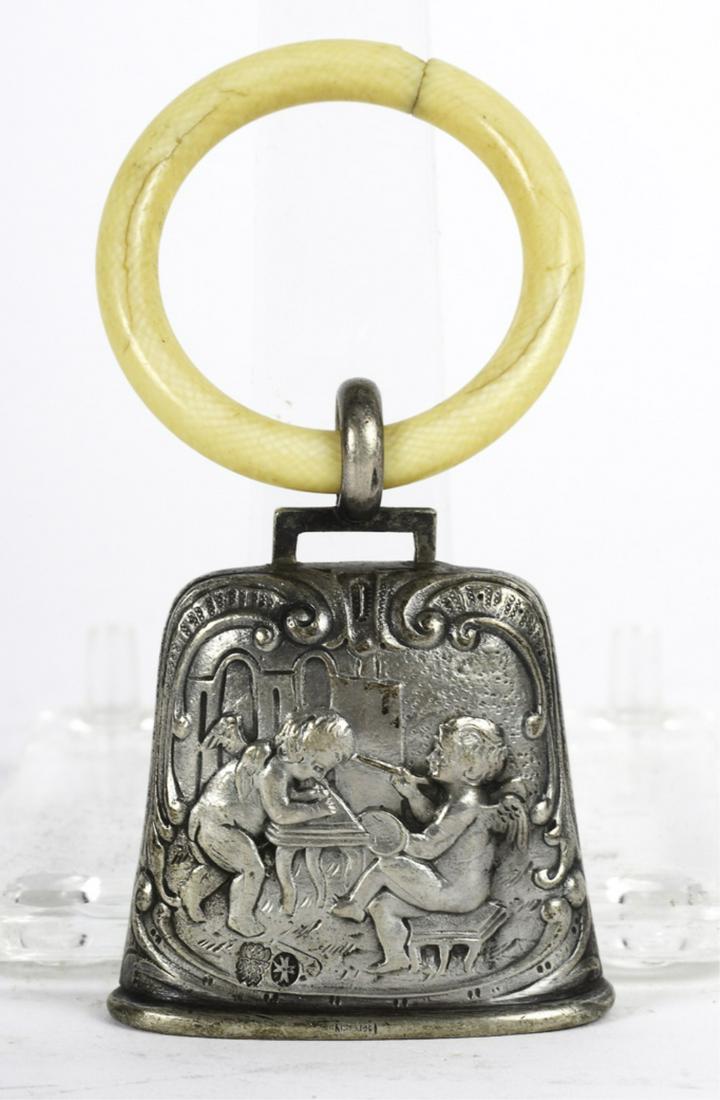TEETHING RING with SILVER BELL: Embossed on each side with cherubs creating artworks. Vereinigte Silberwarenfabriken of Hanau, Germany. 3 1/2 inches.