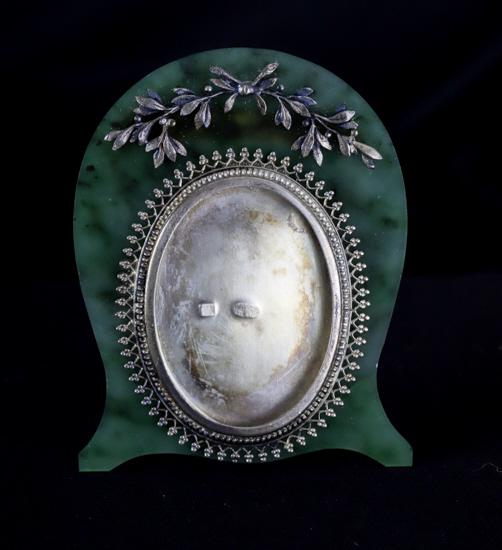 ANDERS JOHAN NEVALAINEN JADE and SILVER FRAME: Jade picture frame mounted with silver laurel bough and oval milgrain bezel. Silver-backed case and stand. 2 5/8 x 2 inches